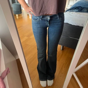 Blå lågmidjade bootcut jeans  - Säljer ett par blå bootcut jeans med snygga kontrastsömmar och broderade bakfickor. Jeansen har låg midja och är i storlek 32. Jeansen är inte mycket använda och finns bara defekter vid hälen på ena benet som man kan se på sista bilden💕💕