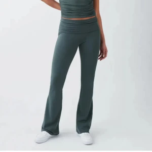 Mörkgröna bootcut byxor från Gina Tricot - Snygga mörkgröna bootcut byxor från Gina Tricot i stretchigt och mjukt material. Hög midja med bred linning och figurnära passform upptill som går ut i ett lätt utsvängda ben. Perfekta för en chill och trendig look.