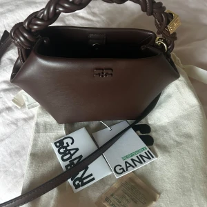Ganni bou bag - Mörkbrun Ganni bag i den ”lilla” versionen! Mycket bra skick, använts sparsamt vid speciella tillfällen!  Dustbag, tagg mm medföljer. Fraktas i en låda!