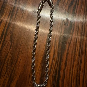 Tjockt silverfärgat halsband med tvinnad kedja - Säljer ett snyggt halsband i silverfärg med tvinnad kedja. Kedjan är 121cm lång och är cirka 4mm - 5 mm tjock 