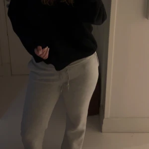 Grå mjukisbyxor med snörning - Säljer ett par ljusgrå mjukisbyxor med dragsko i midjan. Byxorna har en relaxed passform och är tillverkade i mjukt bomullsmaterial. Perfekta för chill dagar hemma eller när du vill vara bekväm men ändå se fräsch ut. Byxorna är väldigt fina att även vika ner som ja gjort på nån av bilderna. 
