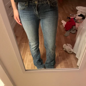 Blå Lee jeans bootcut 29/32 - Säljer ett par klassiska blå jeans från Lee i bootcut-modell. Jeansen har normal passform, fem fickor och snyggt slitna detaljer. Tillverkade i 100% bomull för en autentisk denimkänsla. Perfekta för dig som gillar en tidlös look.