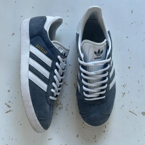 Adidas Gazelle grå sneakers - Tjo, säljer ett par Adidas gazelle. Skorna har använts några gånger men är fortfarande i bra skick. Har du några frågor är det bara att skriva. Kan även gå ner i pris vid en snabb affär. Finns att hämta i Göteborg eller skickas med frakt