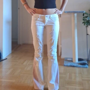 Lågmidjade special-designade vita jeans  - Ett par super snygga och unika vita jeans från ONLY som jag har designat om helt och hållet. Jeansen är lågmidjade, har en massa coola revor och är omsydda till bootcut med snyggt rosa tyg. Passar perfekt till dig som vill ha en cool touch till dina outfits.