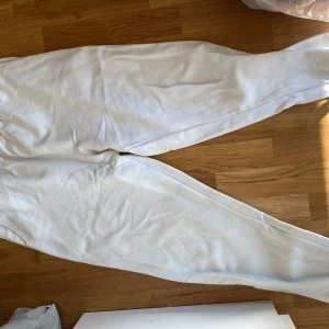 Vita mjukisbyxor med resår - Säljer ett par vita mjukisbyxor med resår i midjan och vid bensluten. Byxorna är i mjukt material och har en avslappnad passform, perfekta för chill dagar hemma eller när du vill vara bekväm. Klassisk look som funkar till det mesta. Kan mötas upp i Trollhättan eller Alingsås. Kan skickas men då tillkommer en fraktkostnad.