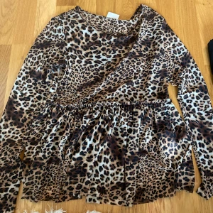 Leopardmönstrad långärmad blus - Säljer en snygg långärmad blus med leopardmönster. Blusen har en lös passform med rynkad midja och är perfekt för dig som vill sticka ut. Färgerna går i brunt, beige och svart och materialet känns mjukt och följsamt.