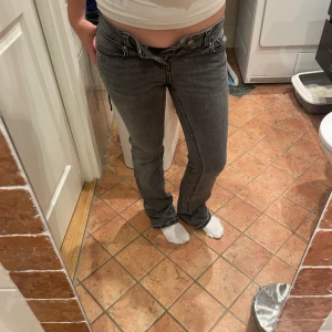 Grå jeans från Gina tricot , stl 36 - Snygga grå jeans från gina tricot i storlek 36. Modellen har låg midja, bootcut med knappar bak. Jeansen är i klassisk denim med svarta sömmar och passar perfekt till en avslappnad stil.