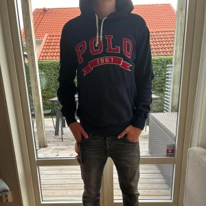 Mörkblå hoodie från Polo Ralph Lauren - Mörkblå hoodie från Polo Ralph Lauren med stor röd POLO logga på bröstet. Klassisk huva med vita snören och känguruficka framtill. Skön passform. Eftertraktad hoodie så se till o inte vänta allt för länge. Priset ej hugget i sten men snabba affärer kommer att prioriteras. Hör gärna av er vid minsta lilla fundering🫶🏻