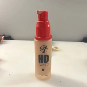 W7 HD Foundation med pump - W7 HD Foundation i en beige nyans, kommer i en smidig plastflaska med röd pump. Ger ett jämnt och täckande resultat som håller länge. Innehåller 30 ml och är vegansk. Perfekt för dig som vill ha en flawless bas med naturlig finish. Det kommer inget lock det är borta