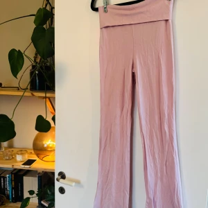 Ljusrosa mjukisbyxor från Gina Tricot - Supersköna ljusrosa mjukisbyxor från Gina Tricot i storlek XXS. Byxorna har hög midja med bred linning och raka ben. Tillverkade i mjukt bomullsmaterial som är perfekt för chill dagar eller när du vill vara extra bekväm.