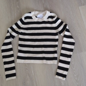 Randig svartvit tröja från Zara - Snygg ribbstickad tröja från Zara i svart och vitt med breda horisontella ränder. Tröjan har rund halsringning och långa ärmar, perfekt för en stilren och trendig look. Passar dig som gillar klassiska mönster och enkel design.