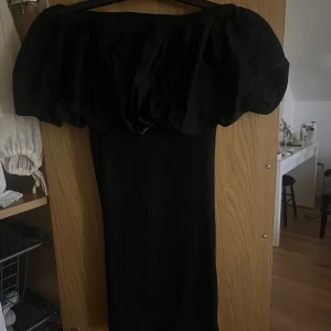 Svart offshoulder klänning från Zara - Supersnygg svart klänning med offshoulder-modell och puffig överdel. Klänningen har en tight passform nedtill och ger en riktigt elegant siluett. Perfekt för dig som vill sticka ut med en dramatisk look.