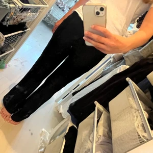 Svarta byxor från Grunt - Svarta byxor från Grunt i storlek L med snyggt hålmönster över hela tyget. Byxorna har rak/bootcut passform och elastisk midja för extra komfort. Perfekta för dig som vill ha något unikt och stilrent i garderoben.