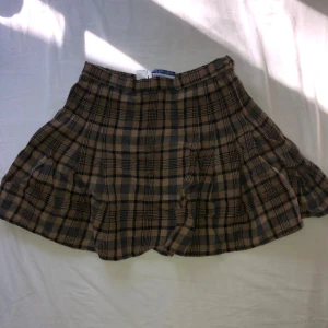 Rutig ullkjol från Pendleton - Superfin kort rutig kjol från Pendleton i 100% ull. Kjolen har beige, bruna och svarta toner och klassiskt rutmönster. 