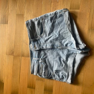Ljusblå jeansshorts från H&M - Snygga ljusblå jeansshorts från H&M. De har hög midja, upprullade benslut och slitna detaljer .