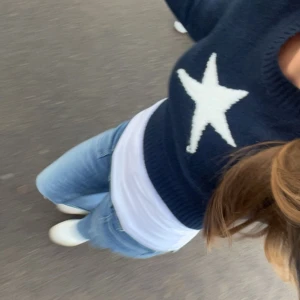 Mörkblå croppad stickad tröja med stjärna - Mörkblå croppad stickad tröja från FB Sister med en stor vit stjärna på bröstet. Tröjan har rund halsringning, långa ärmar och bred ribbad mudd nertill. Perfekt för dig som gillar en trendig och avslappnad stil.