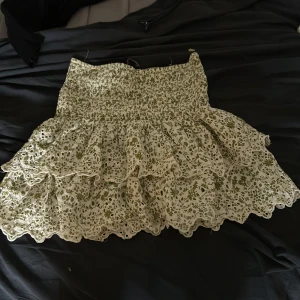 Blommig volangkjol  - Supersöt kort kjol med volanger och blommigt mönster i grönt och vitt. 