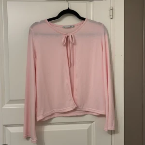 Ljusrosa kofta med knyt framtill - Supersöt ljusrosa kofta från Lager 157, med långa ärmar och knytband framtill. Koftan är tunn och mjuk, perfekt för lager-på-lager och har en enkel, stilren design. Passar dig som gillar en feminin och chill vibe.