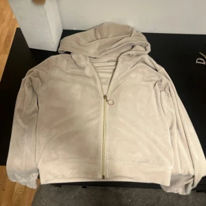 Beige hoodiejacka från Gina Tricot - Mjuk och skön beige hoodiejacka från Gina Tricot med dragkedja i guld och huva. Jackan är i ett lent material som känns lyxigt och har en enkel, clean look. Perfekt för dig som gillar en chill och stilren vibe.