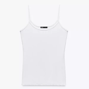 Vit linnetopp från Zara - En klassisk vit linnetopp från Zara med smala axelband och rundad halsringning. Enkel och stilren design som är lätt att matcha med allt. Perfekt för varma dagar eller som lager under skjortor och jackor. Typ oanvänd