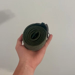 Snyggt grönt bälte  - Snyggt grönt bälte med flätad design och silverfärgat metallspänne. Bältet är gjort i ett hållbart tygmaterial med detaljer i grönt skinn vid spännet🤵🏼 Perfekt accessoar för att lyfta din outfit med en cool touch😎