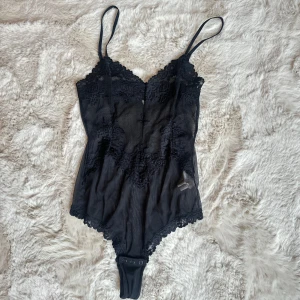 Svart spetsig bodysuit med tunna band - Säljer en svart bodysuit med tunna axelband och v-ringad spetskant. 🖤