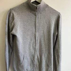 Grå kofta med dragkedja från MNG - En stilren grå kofta från MNG med hel dragkedja framtill och två fickor. Hög ribbad krage och långärmad modell i mjuk bomullsblandning. 