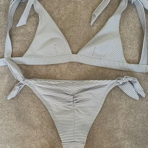 Randig bikini med knyt från H&M - Snygg bikini från H&M i ljusblått och vitt med smala ränder. Bikiniunderdelen har scrunch vid rumpan. Superfin sommarfärg!!☺️💗