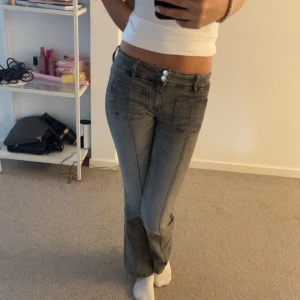 Gråa bootcut jeans med fickor fram från gina - Säljer ett par gråa jeans med bootcut-modell och snygga framfickor. Storlek 158/164. Jeansen har två knappar i midjan och markerade sömmar längs benen. Sitter snyggt på och är perfekta för dig som gillar en klassisk men trendig look.