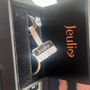 Klassiskt ring set i sterlingsilver Jeulia - Säljer ett elegant ring set från Jeulia i sterlingsilver. Ena ringen har en stor, gnistrande rund sten i solitärfattning och den andra är dekorerad med små klara stenar runt hela bandet. Perfekt för dig som gillar stilren och tidlös design.