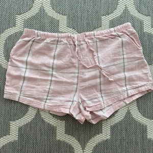 Rosa rutiga pyjamas shorts från Gina Tricot - Söta rosa shorts från Gina Tricot med vitt och grått rutmönster. Använd och tvättad. Använd ungefär 3-5 gånger. Finns ej på Gina Tricots hemsida längre. 