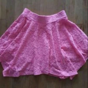 Spetskjol - Supersöt rosa kortkjol med volang och spetsdetaljer. Kjolen har en bred resår i midjan och är perfekt för dig som vill ha en feminin och lekfull stil. Passar extra bra till vår och sommar!