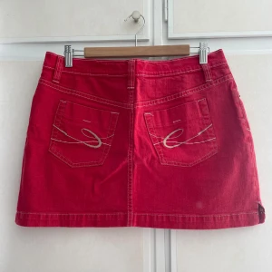 Röd vintage jeanskjol från edc by Esprit - Snygg röd jeanskjol från edc by Esprit med klassisk femficksmodell, vita kontrastsömmar och broderade bakfickor. Kjolen är kort och har knapp- och dragkedjestängning framtill. Perfekt för dig som vill ha en färgklick i garderoben! Storlek 40 men passar 36/38
