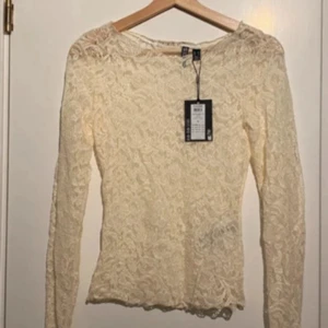 Vit spetsblus från Pieces XS! - Prislappar kvar! Supersöt vit spetsblus från Pieces i storlek XS. Blusen har lång ärm, rund halsringning och är helt täckt av vackert spetsmönster. Perfekt för dig som gillar romantisk och feminin stil. Materialet är mjukt och stretchigt för en bekväm passform.