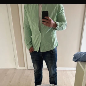 Mintgrön Ralph Lauren skjorta - Fräsch mintgrön skjorta från Polo Ralph Lauren i slim fit. Klassisk modell med knappar hela vägen, lång ärm och broderad logga på bröstet. Skjortan är i mjuk bomull och passar perfekt till jeans eller chinos.