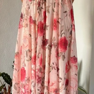 Blommig långklänning från Amisu - Superfin långklänning från Amisu i ljusa toner med romantiskt blommigt mönster i rosa, rött och beige. Klänningen har ett luftigt fall och är perfekt för sommarens alla tillfällen. Materialet känns lätt och svalt mot huden.