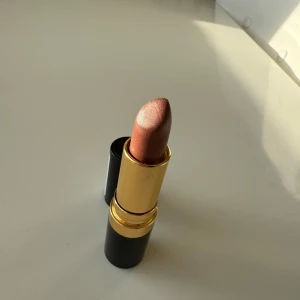Revlon Lipstick - Caramel Glacé - Revlon Super Lustrous Lipstick i färgen 103 Caramel Glacé.  Ett pärlemorskimrande läppstift i varm karamellbrun nyans. Perfekt för dig som gillar en mjuk, glansig finish och vill ha en naturlig men ändå glammig look.  Endast använd lite grann. Mycket bra skick.  Originalpris: 160 kr Mitt pris: 49 kr