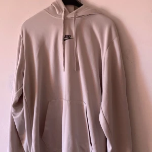 Beige Nike hoodie med zebradetaljer - Snygg beige hoodie från Nike med svart logga på bröstet och zebramönstrade detaljer längs ärmarna. Tröjan har huva med snörning och en stor magficka. Perfekt för dig som gillar streetwear och vill sticka ut lite extra. Har inte använt den så mycket! Den ser fortfarande helt ny ut! 