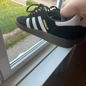 Adidas Spezial svarta sneakers mocka - Svarta Adidas Spezial sneakers i mocka med klassiska vita ränder på sidorna och guldfärgad Spezial-logga. Knappt använda, helt i nyskick!!!!! Ta till beaktning i priset. 