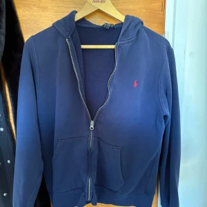Marinblå hoodie från Polo Ralph Lauren - Säljer en marinblå hoodie från Polo Ralph Lauren med dragkedja och huva.                                                Pris kan diskuteras 