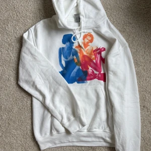Vit hoodie med färgglatt tryck - Vit hoodie från In Print We Trust med stort färgglatt tryck av två personer i blått, orange och rosa på . Jättefin verkligen men knappt använd🥰