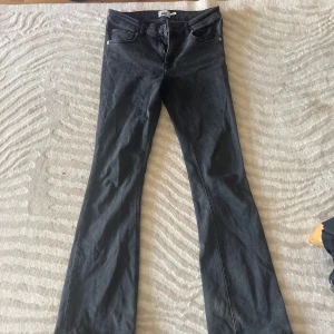 Svarta bootcut jeans med slitna detaljer - Snygga svarta jeans med bootcut-modell och klassisk femficksdesign. Jeansen har slitna detaljer vid benslutet för en cool, avslappnad look. Perfekta för dig som gillar en lite mer edgy stil och vill ha ett par jeans som sticker ut.