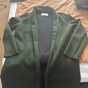 Mörkgrön kappa från Stradivarius - Snygg mörkgrön kappa från Stradivarius i storlek S. Jackan har en rak och enkel design utan knappar, med långa ärmar och mjukt material som ger en clean look. 