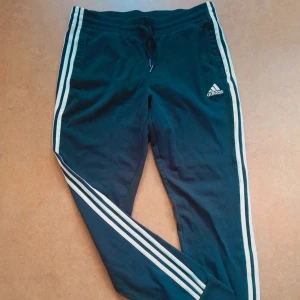 Byxor från Adidas Performance - Ett par svarta mjukis/träningsbyxor med de klassiska vita ränderna på sidorna, från Adidas Performance. Storlek M. Fickor samt dragsko i midjan. Köpta på Zalando för 569 kr, endast använda och tvättade en gång så i princip i nyskick. Här ser du hur de ser ut på en modell: https://www.zalando.se/adidas-performance-traeningsbyxor-blackwhite-ad541e1qi-q11.html