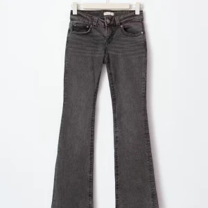 Grå bootcut jeans med låg midja - Snygga grå jeans med bootcut-modell och låg midja. Jeansen har klassisk femficksdesign och är tillverkade i ett mjukt denimtyg. Perfekta för dig som gillar en retro vibe och vill ha ett par jeans som sticker ut.