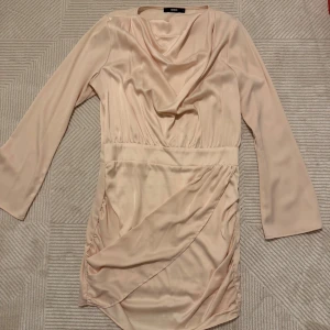 Klänning  - Snygg kort klänning från Bik Bok satinlook. Klänningen har långa ärmar, och draperad front som ger en elegant vibe. 