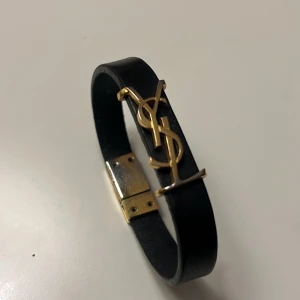 YSL armband  - Säljer nu mitt YSL armband som jag köpte på NK i Göteborg 2022 som inte kommer till användning. (Str: S = 16cm) Det har försvunnit lite av guld pläteringen på loggan och vid låset. Inget man tänker på du bär det. Går att lämna in på reparation på NK. Hör av dig om du är intresserad!