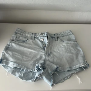 Ljusblå jeansshorts med fransig kant - Snygga ljusblå jeansshorts med medelhög midja och fransig kant nertill. Storlek 38/M, men passar även S om man vill ha lite lösare💗