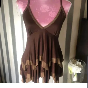 Brun volangtop från Zara Collection - Supersöt brun topp från Zara Collection med volanger i två nyanser av brunt. Djup v-ringning, smala axelband och flowig passform. Perfekt för dig som gillar en bohemisk och lekfull stil. Tillverkad i mjukt material som känns skönt mot huden.