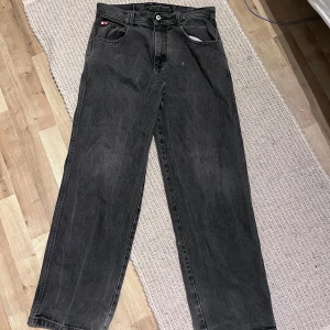 Southpole red tabs - Svarta jeans från Southpole i loose fit med raka ben och klassisk femficksdesign. Jeansen har en något tvättad look och slitna detaljer vid bensluten. Tillverkade i bomull för en skön känsla och streetig vibe.